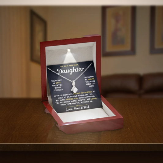 To Our Amazing Daughter necklace from Mom & Dad in a lit mahogany gift box on a wooden table