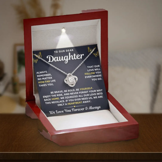 To Our Daughter necklace from Mom & Dad in a lit mahogany gift box on a wooden table
